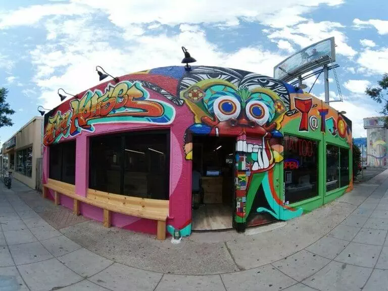 A brightly colored building with vibrant murals, featuring a cartoonish face, 