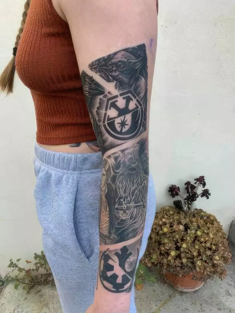 Person's arm with detailed Star Wars-themed tattoos, including Yoda, Chewbacca, and Galactic Empire symbols, wearing a brown sleeveless top and gray sweatpants. Background includes a plant against a white wall.