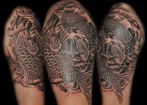 Photo of a detailed black and grey tattoo depicting two koi fish surrounded by swirling water on a person's upper arm.