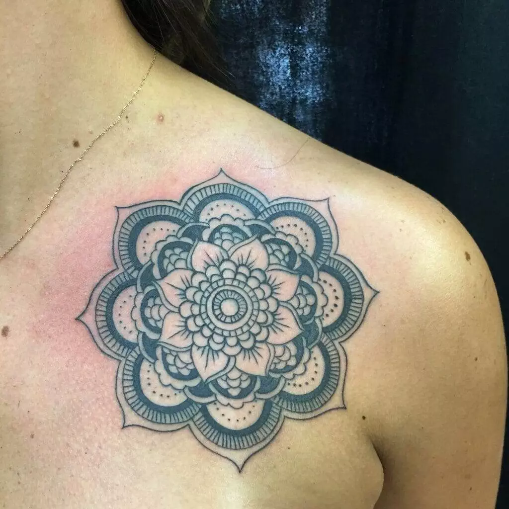 A detailed mandala tattoo with floral patterns is inked on the upper shoulder and chest area.