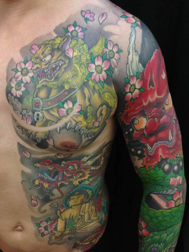 A person with an extensive upper body tattoo featuring a Japanese dragon, a Foo dog, a Buddha, and various floral designs.