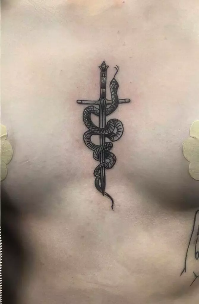 Black ink tattoo on a person's chest depicting a sword with a snake coiled around it.