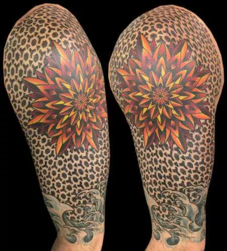 Two tattooed arms featuring a symmetrical, colorful starburst design over a cheetah print background, with grey and black swirling patterns near the wrists.