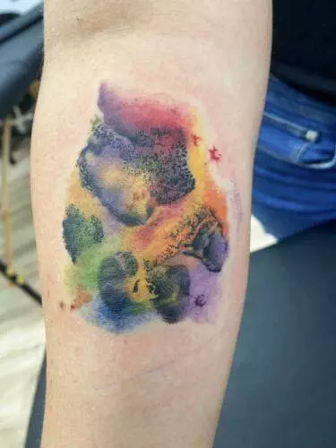 A forearm tattoo featuring abstract, colorful watercolor splashes and silhouettes of four bear heads in various poses.