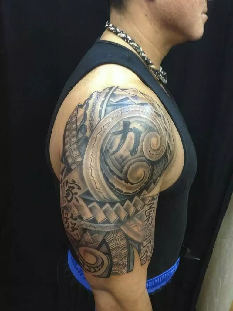 A person with a large, detailed tribal tattoo covering the upper arm and shoulder, wearing a sleeveless top, stands in profile against a dark background.