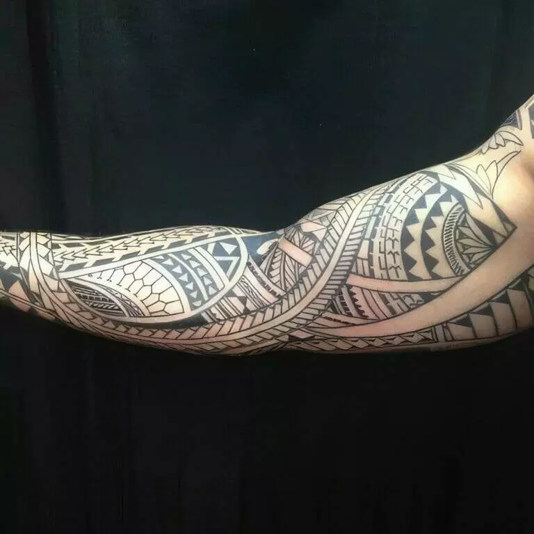 An arm with an intricate tribal tattoo design featuring geometric patterns and bold lines.