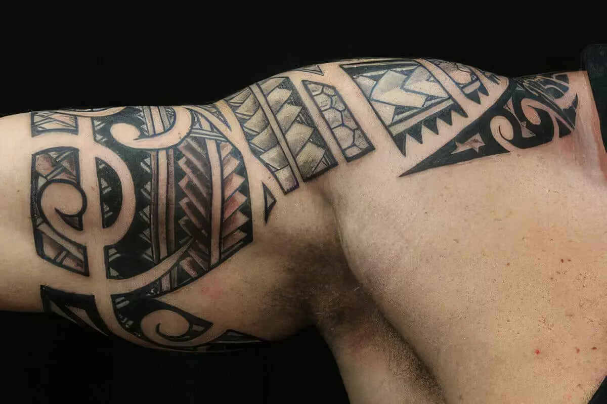 A close-up image of a person's upper arm displaying an intricate Polynesian tribal tattoo design in black ink.