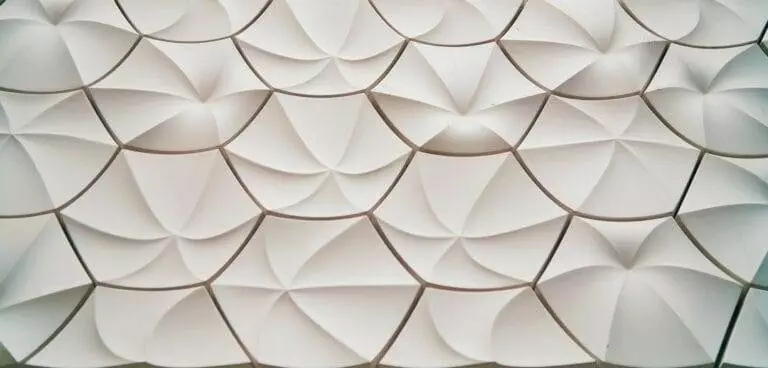 A close-up view of an abstract, white, geometric pattern featuring overlapping, petal-like shapes.