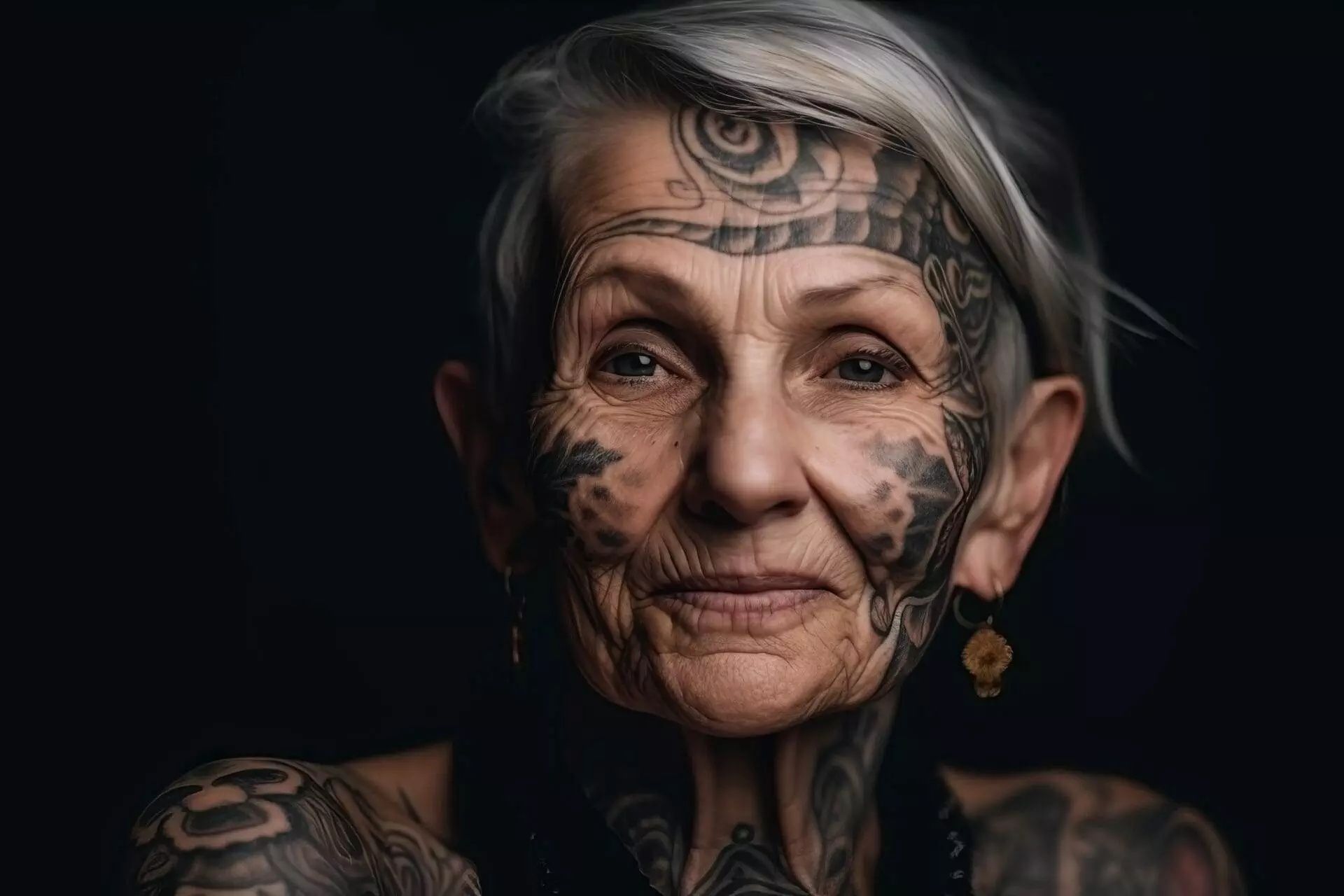 An elderly person with short gray hair and various facial and body tattoos is depicted against a dark background. They are wearing a black top and earrings.