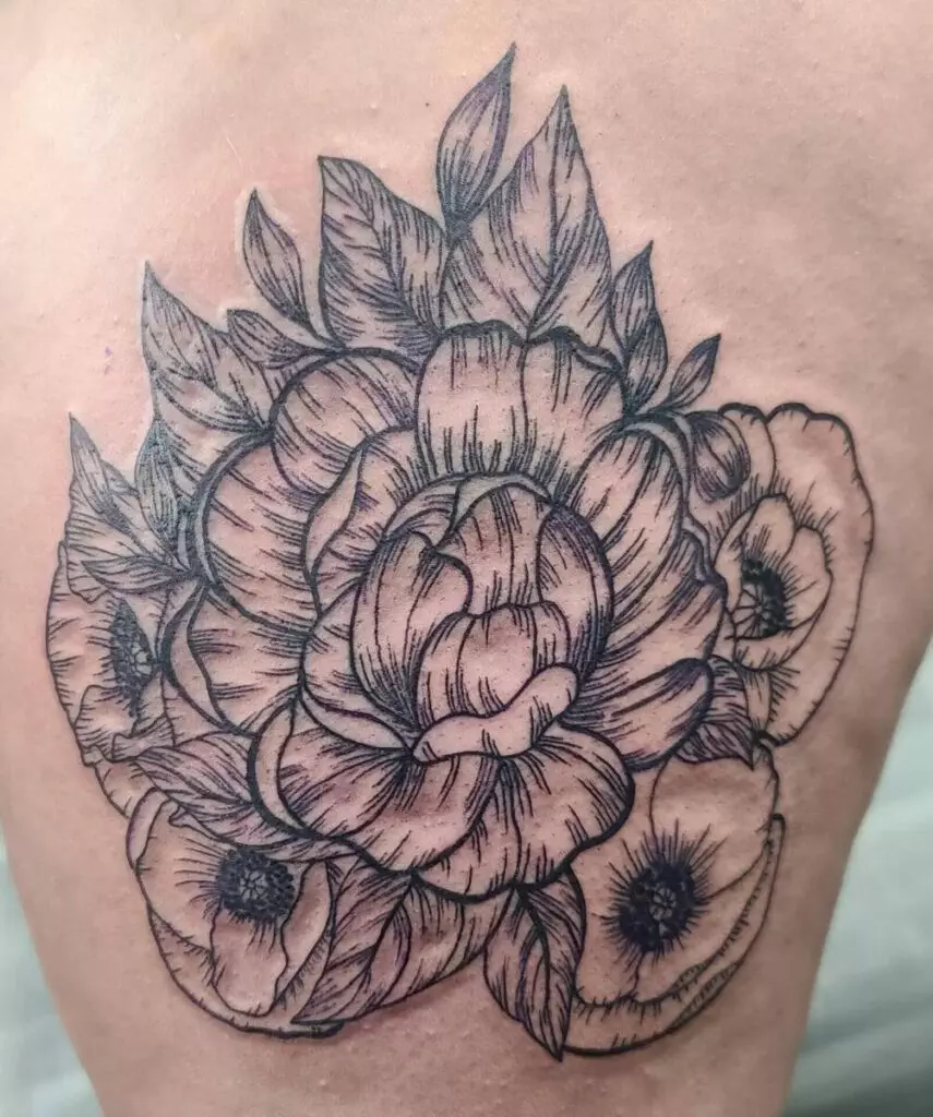 A black and gray tattoo featuring a cluster of blooming roses and other flowers with intricate detailing on petals and leaves.