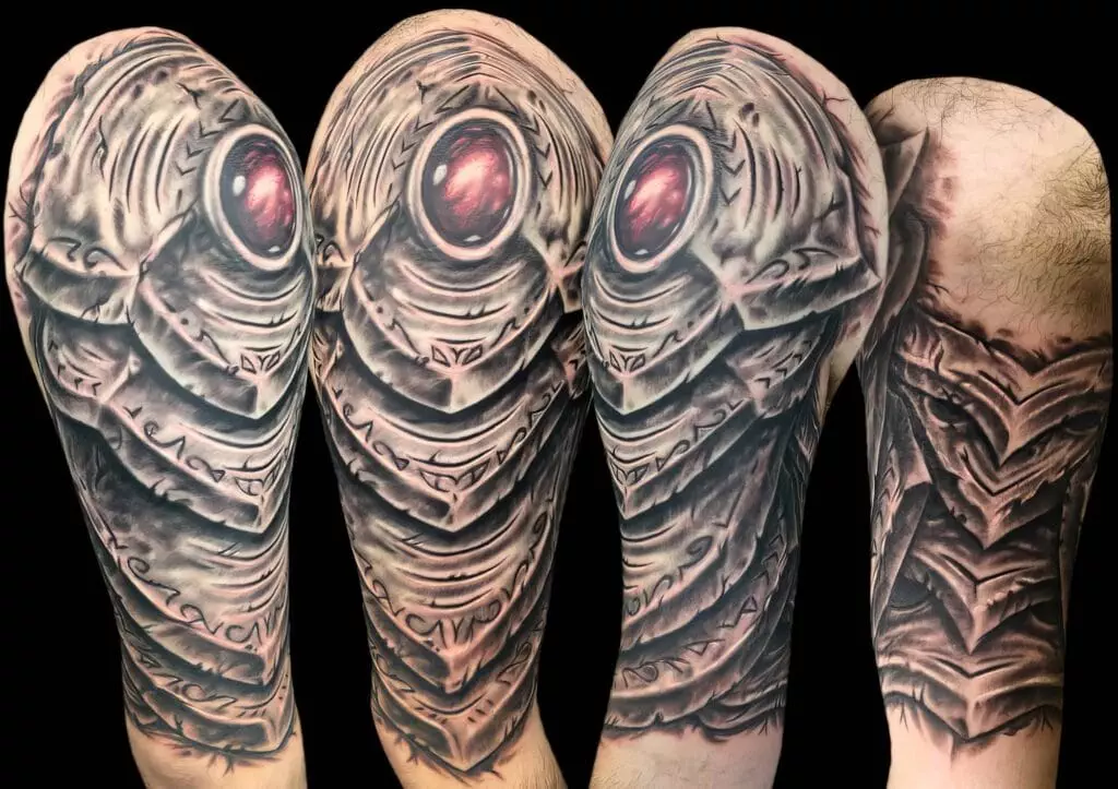 Close-up view of a sci-fi themed sleeve tattoo featuring a detailed, robotic design with a glowing red orb in the center, shown from multiple angles.