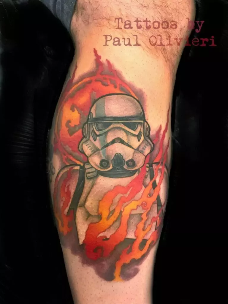 Tattoo of a stormtrooper helmet surrounded by flames on a person's leg, with the text 