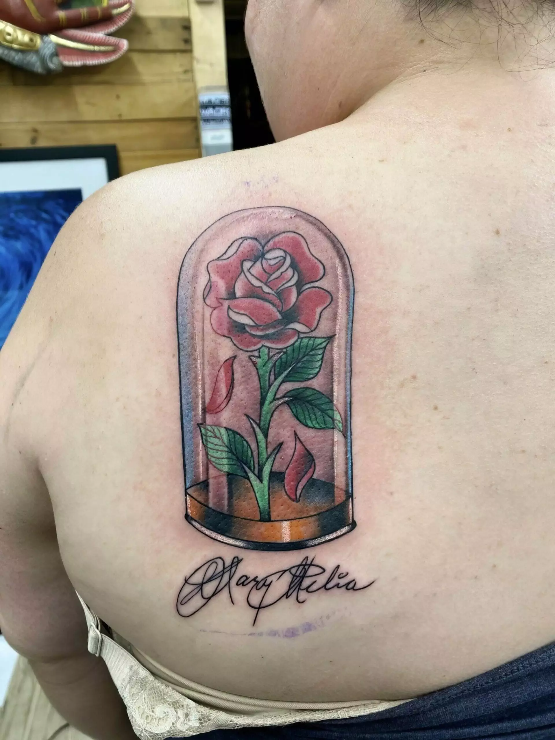 Tattoo of a rose enclosed in a glass dome with the name 